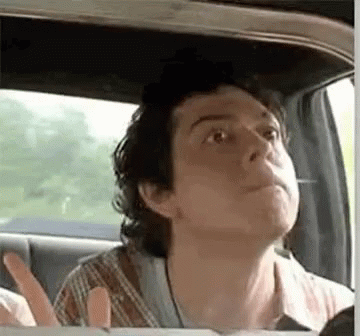 A Man Is Sitting In The Back Seat Of A Car Looking Up At The Sky . GIF