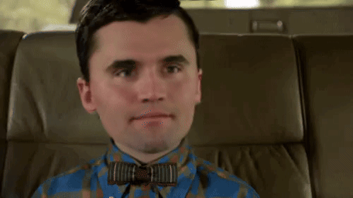 A Man Is Sitting In The Back Seat Of A Car Tying A Bow Tie . GIF