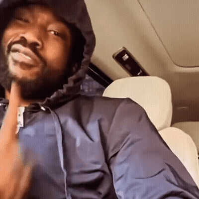 A Man Is Sitting In The Back Seat Of A Car Wearing A Hooded Jacket . GIF