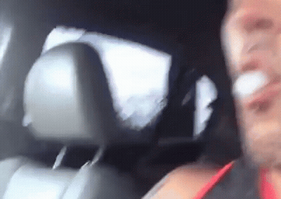A Man Is Sitting In The Back Seat Of A Car With A Bandage On His Face . GIF