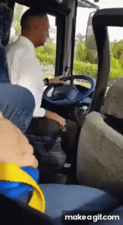 A Man Is Sitting In The Driver 'S Seat Of A Bus While A Child Sits In The Back Seat . GIF
