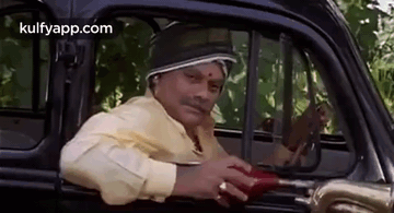 A Man Is Sitting In The Driver 'S Seat Of A Car And Holding An Umbrella . GIF