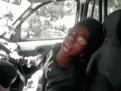 A Man Is Sitting In The Driver 'S Seat Of A Car And Making A Funny Face . GIF