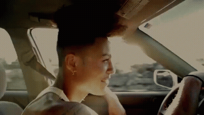 A Man Is Sitting In The Driver 'S Seat Of A Car Looking Out The Window . GIF