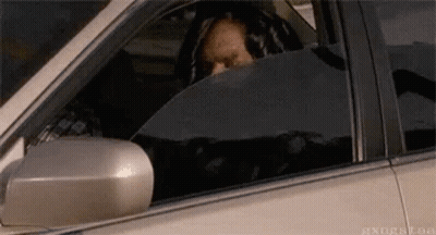 A Man Is Sitting In The Driver 'S Seat Of A Car Looking Out The Window . GIF