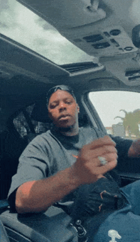 A Man Is Sitting In The Driver 'S Seat Of A Car GIF
