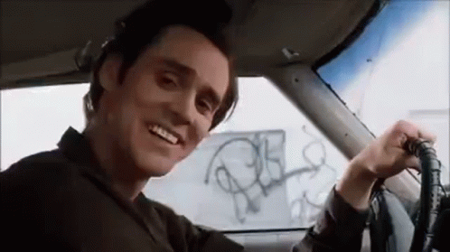 A Man Is Sitting In The Driver 'S Seat Of A Car Smiling . GIF