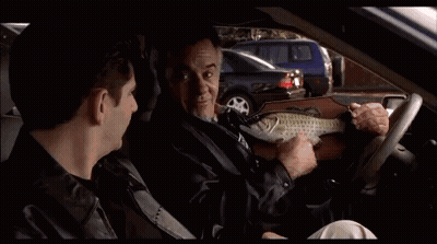 A Man Is Sitting In The Driver 'S Seat Of A Car With Another Man . GIF