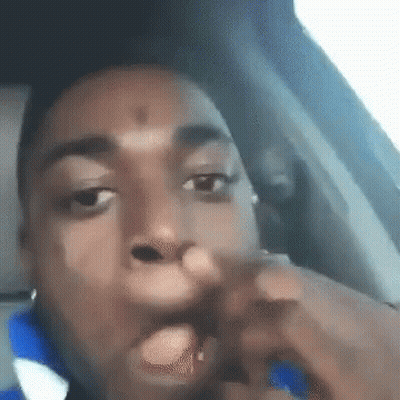 A Man Is Sitting In The Driver 'S Seat Of A Car With His Hand In His Mouth . GIF