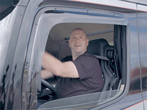 A Man Is Sitting In The Driver 'S Seat Of A Truck And Smiling . GIF