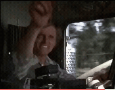 A Man Is Sitting In The Driver 'S Seat Of A Truck With His Hand In The Air GIF