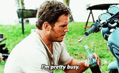 A Man Is Sitting Next To A Motorcycle And Says " I 'M Pretty Busy " GIF
