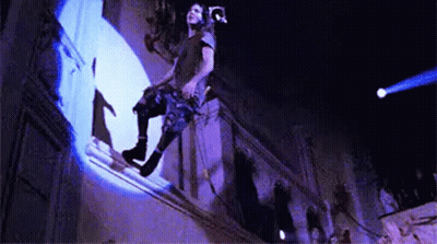 A Man Is Sitting On A Balcony With A Camera On His Head . GIF