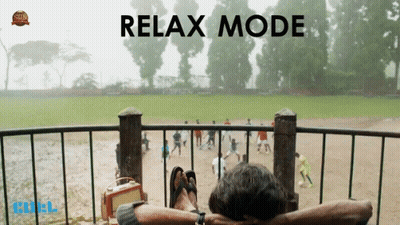A Man Is Sitting On A Balcony With His Feet Up And The Words Relax Mode Behind Him GIF