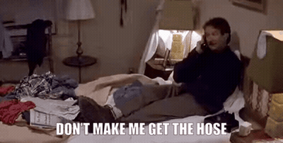 A Man Is Sitting On A Bed Talking On A Cell Phone . GIF