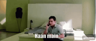 A Man Is Sitting On A Bed Talking On A Cell Phone With The Words Haan Main . GIF