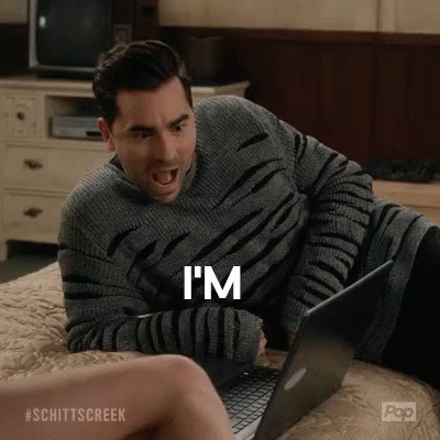A Man Is Sitting On A Bed Using A Laptop Computer And Yelling . GIF