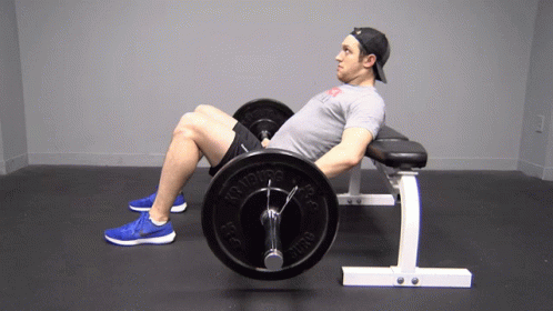 A Man Is Sitting On A Bench Holding A Barbell That Says Nitro On It GIF
