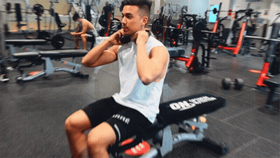 A Man Is Sitting On A Bench In A Gym That Says Orlstrom GIF