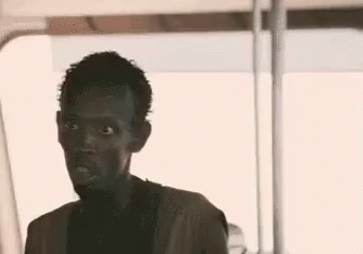 A Man Is Sitting On A Bus And Looking At The Camera . GIF