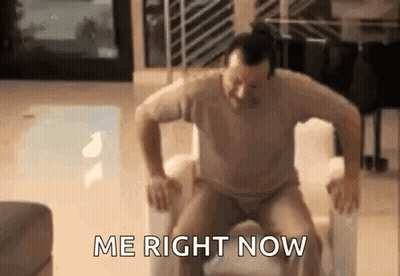 A Man Is Sitting On A Chair With His Legs Crossed And The Words `` Me Right Now '' Written On The Screen . GIF