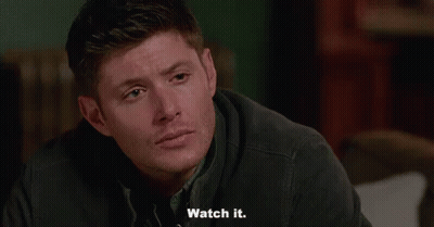 A Man Is Sitting On A Couch And Saying `` Watch It '' While Looking At The Camera . GIF
