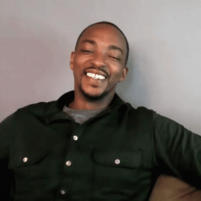 A Man Is Sitting On A Couch And Smiling With His Eyes Closed . GIF