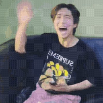 A Man Is Sitting On A Couch Holding A Cell Phone And Making A Funny Face . GIF