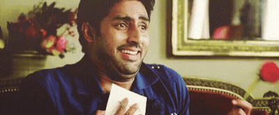 A Man Is Sitting On A Couch Holding A Piece Of Paper And Making A Funny Face . GIF