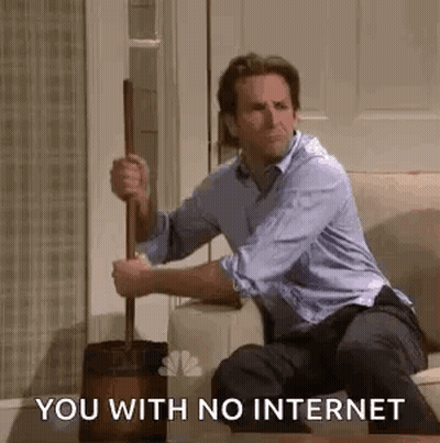 A Man Is Sitting On A Couch Holding A Toilet Brush And A Mop . GIF