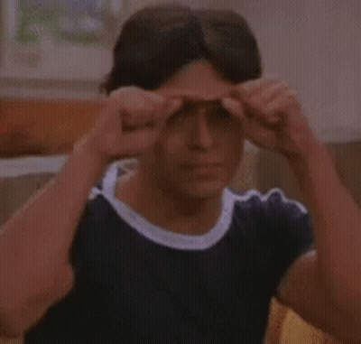 A Man Is Sitting On A Couch Holding His Hands To His Eyes . GIF