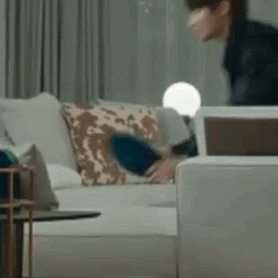 A Man Is Sitting On A Couch In A Living Room With A Laptop . GIF