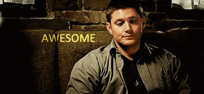 A Man Is Sitting On A Couch In Front Of A Sign That Says Awesome On It GIF