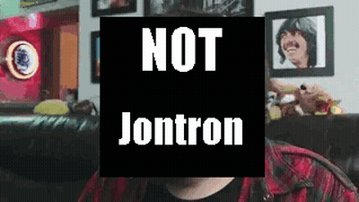 A Man Is Sitting On A Couch In Front Of A Sign That Says Not Jontron . GIF