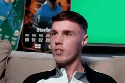 A Man Is Sitting On A Couch In Front Of A Sterling Card GIF