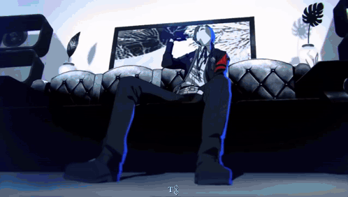A Man Is Sitting On A Couch In Front Of A Tv With The Letter T On The Bottom Right GIF