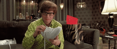 A Man Is Sitting On A Couch Looking At A Pair Of Shoes GIF
