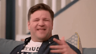 A Man Is Sitting On A Couch Making A Funny Face While Laughing . GIF