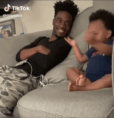 A Man Is Sitting On A Couch Next To A Baby Who Is Sitting On The Couch . GIF