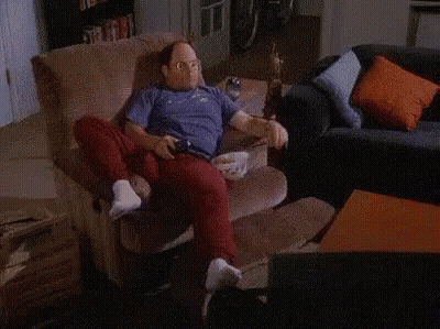 A Man Is Sitting On A Couch Next To A Shelf Full Of Sodas And Snacks GIF