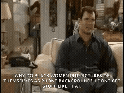 A Man Is Sitting On A Couch Talking To A Woman While Holding A Telephone . GIF