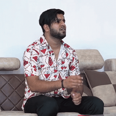 A Man Is Sitting On A Couch Wearing A Shirt That Says ' A ' On It GIF