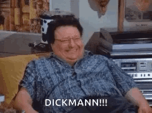 A Man Is Sitting On A Couch With A Record Player In The Background And Laughing . GIF