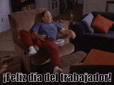 A Man Is Sitting On A Couch With A Shelf Full Of Cans Of Beer . GIF