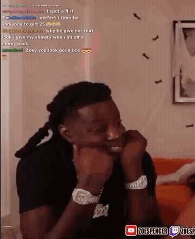 A Man Is Sitting On A Couch With His Hands On His Face And Looking At The Camera . GIF