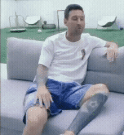 A Man Is Sitting On A Couch With His Legs Crossed GIF