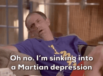 A Man Is Sitting On A Couch With His Legs Crossed And Says Oh No I 'M Sinking Into A Martian Depression GIF