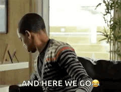 A Man Is Sitting On A Couch With The Words `` And Here We Go '' Written On It . GIF