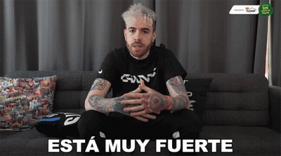 A Man Is Sitting On A Couch With The Words " Esta Muy Fuerte " Written On The Bottom GIF