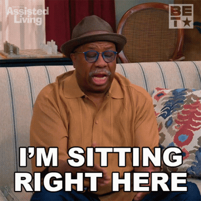 A Man Is Sitting On A Couch With The Words I 'M Sitting Right Here GIF